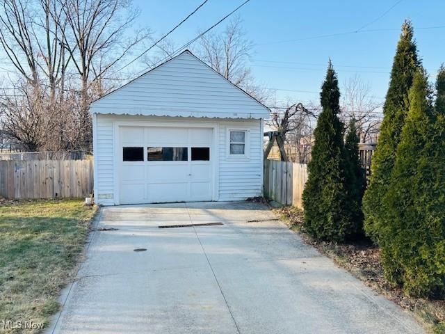 detached garage featuring driveway and fence