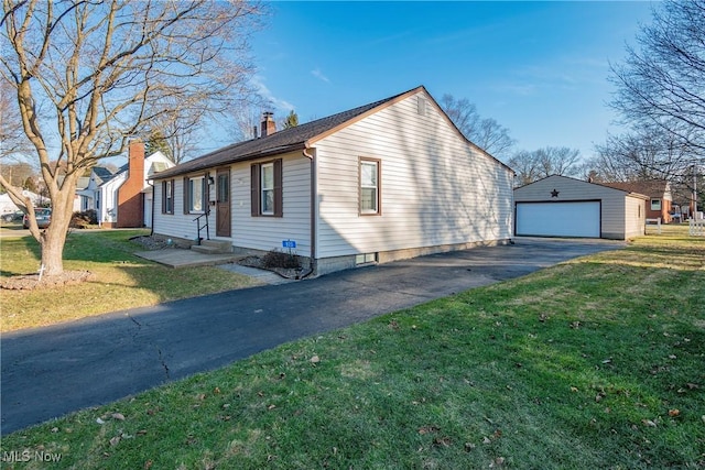 view of side of home featuring entry steps, a chimney, a yard, a garage, and an outdoor structure