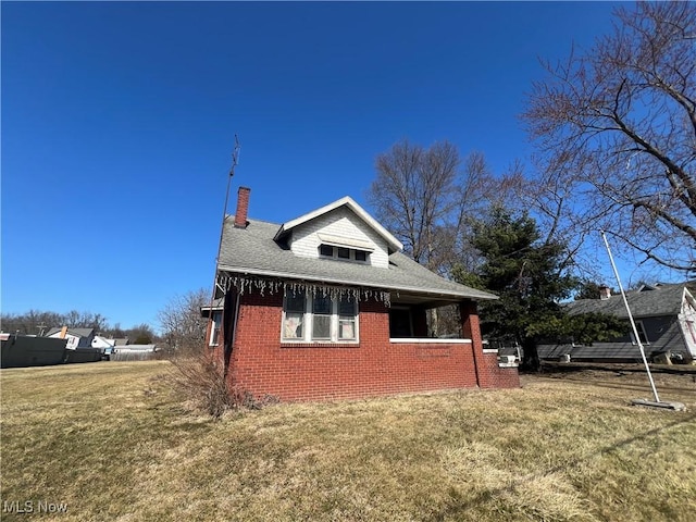 view of side of home featuring a lawn, brick siding, roof with shingles, and a chimney