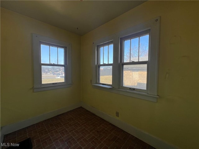 empty room featuring brick patterned floor and baseboards