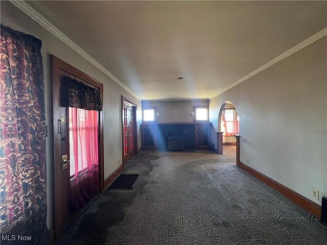 empty room featuring arched walkways, baseboards, carpet floors, and ornamental molding