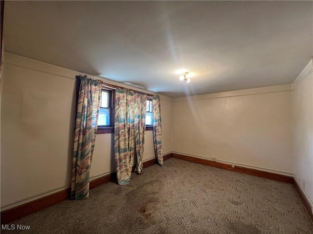 spare room featuring carpet flooring and baseboards