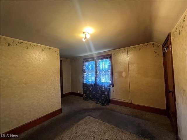 unfurnished room featuring dark carpet and vaulted ceiling