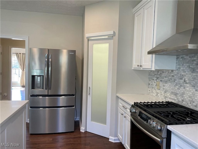 kitchen featuring backsplash, stainless steel appliances, white cabinets, wall chimney range hood, and dark wood-style flooring