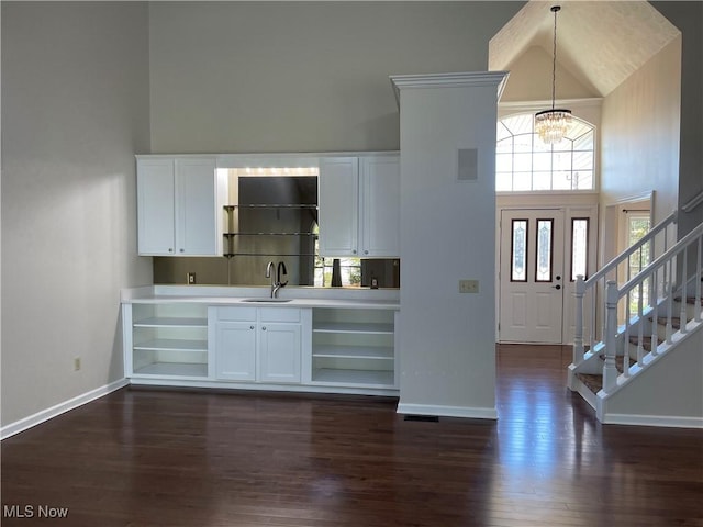 bar with a sink, a high ceiling, an inviting chandelier, and dark wood-style flooring