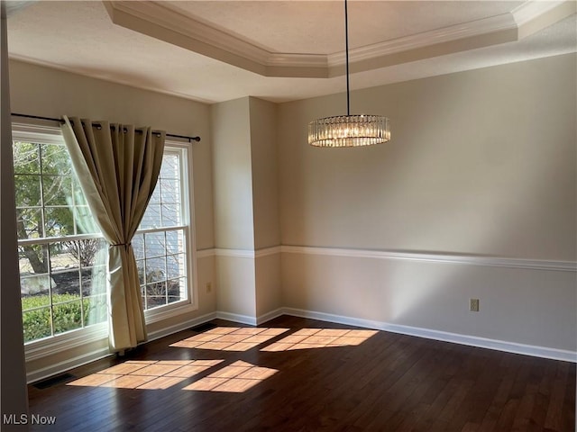 unfurnished room featuring a tray ceiling, dark wood-type flooring, visible vents, and ornamental molding