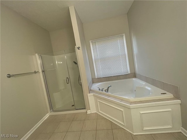 full bath with tile patterned flooring, a stall shower, a textured ceiling, and a garden tub