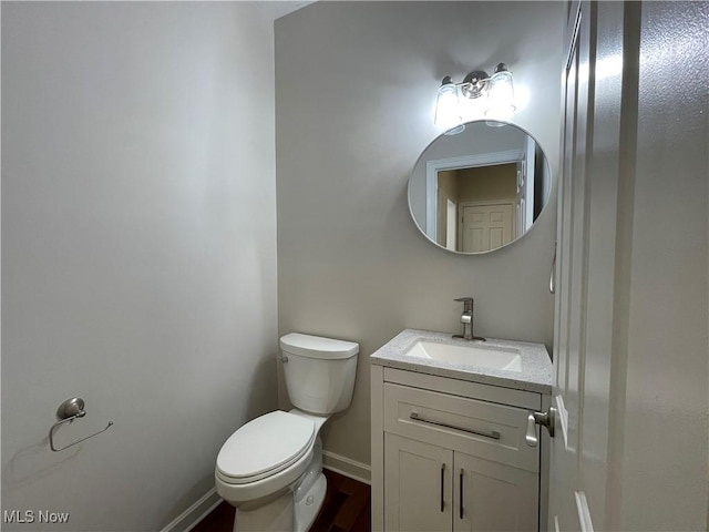 half bathroom featuring toilet, vanity, and baseboards