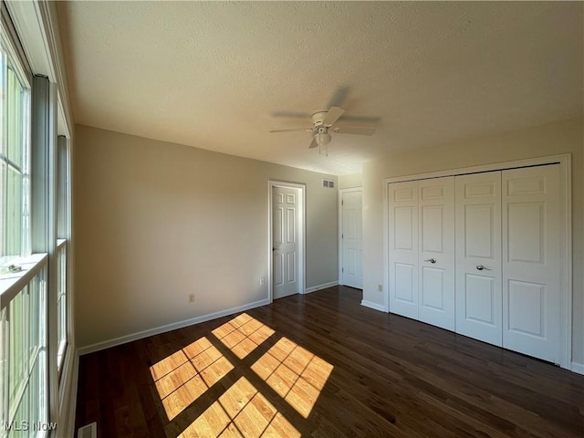 unfurnished bedroom featuring dark wood-style floors, visible vents, a textured ceiling, and baseboards