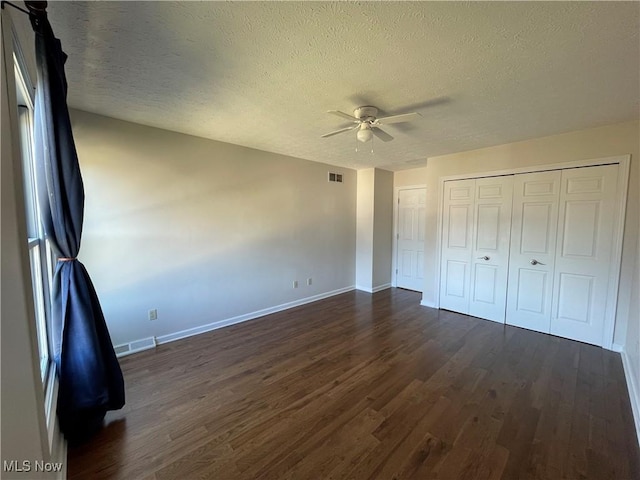 unfurnished bedroom featuring dark wood finished floors, baseboards, visible vents, and a textured ceiling