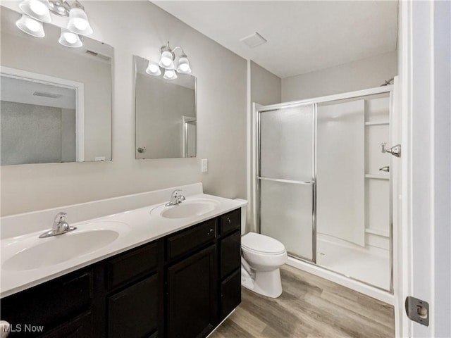 full bathroom featuring toilet, wood finished floors, a stall shower, and a sink