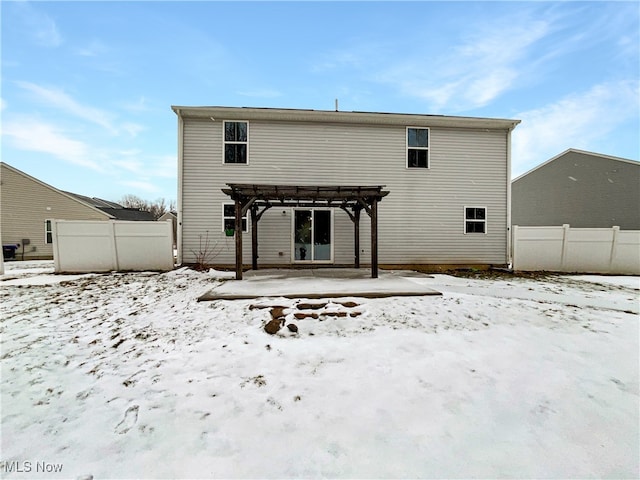 snow covered house with a pergola and fence