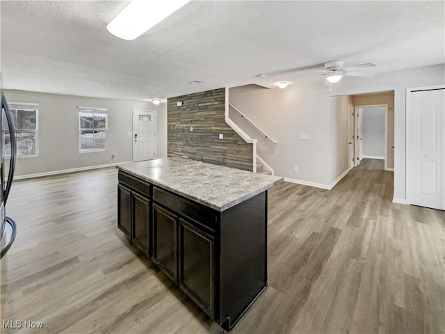 kitchen with open floor plan, a textured ceiling, light countertops, and light wood-style floors