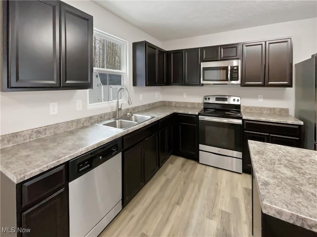 kitchen with a sink, light countertops, light wood finished floors, and stainless steel appliances