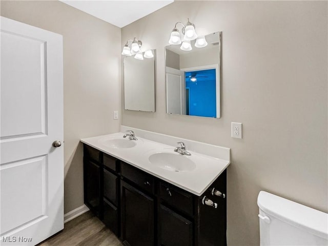 bathroom with double vanity, wood finished floors, toilet, and a sink