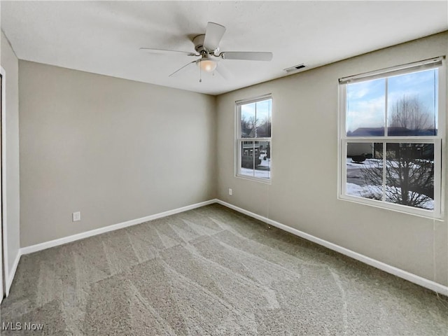 spare room featuring a healthy amount of sunlight, visible vents, carpet floors, and baseboards