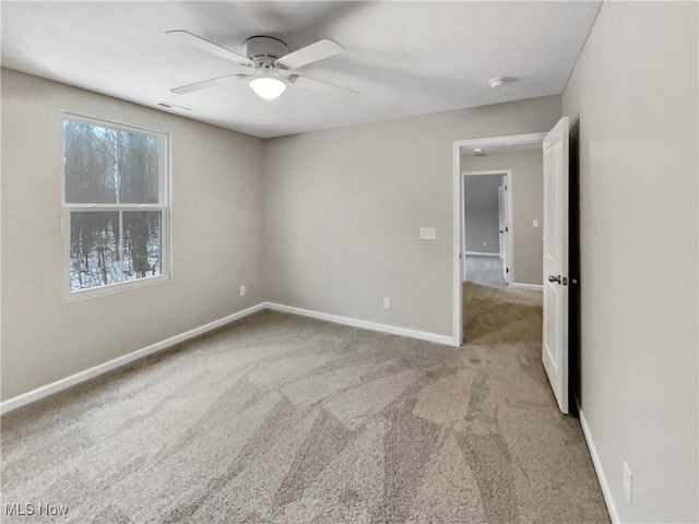 carpeted spare room featuring visible vents, a ceiling fan, and baseboards