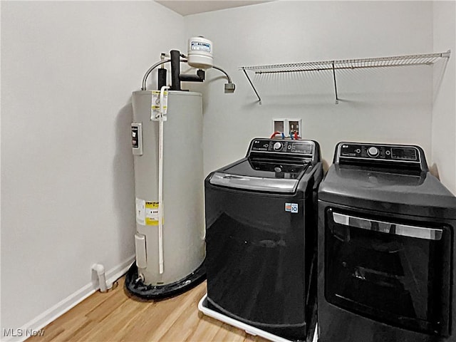 washroom with wood finished floors, baseboards, washing machine and clothes dryer, laundry area, and water heater