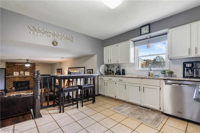 kitchen featuring light tile patterned floors, tasteful backsplash, stainless steel dishwasher, and white cabinetry