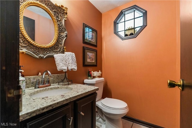 half bathroom featuring tile patterned flooring, toilet, and vanity