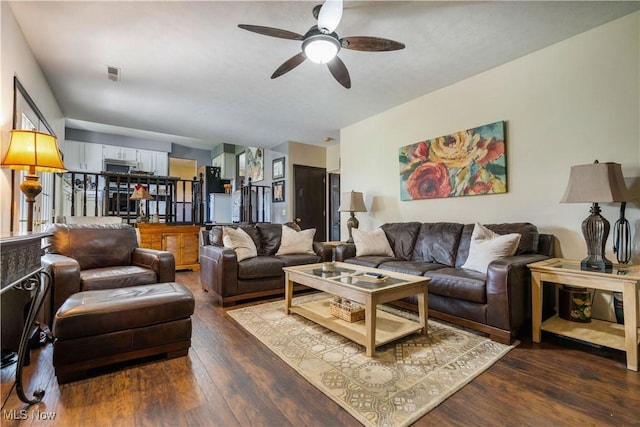 living room featuring dark wood-type flooring, visible vents, and ceiling fan