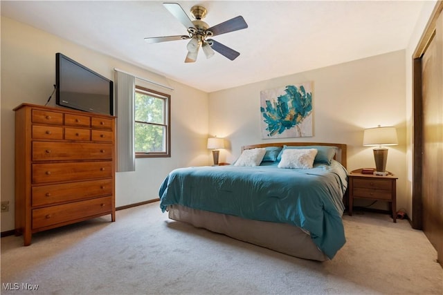 bedroom featuring light colored carpet, baseboards, and ceiling fan