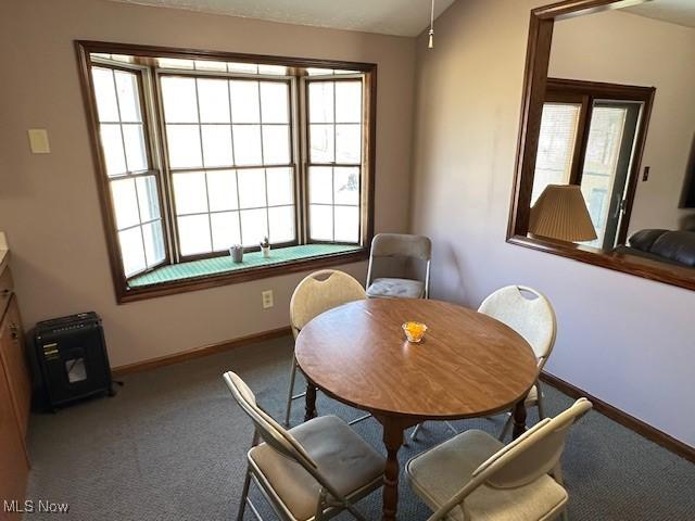 carpeted dining room featuring lofted ceiling and baseboards