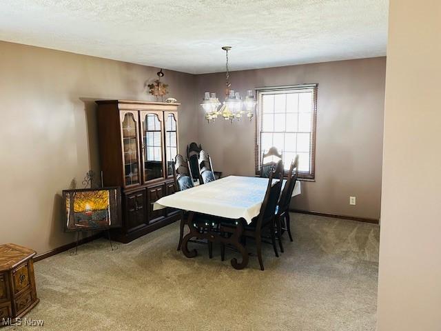 carpeted dining room with baseboards, a textured ceiling, and a chandelier