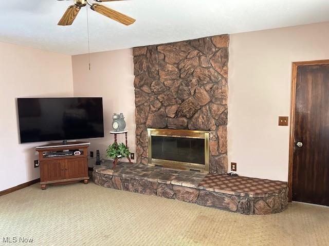 carpeted living area featuring baseboards, a ceiling fan, and a fireplace