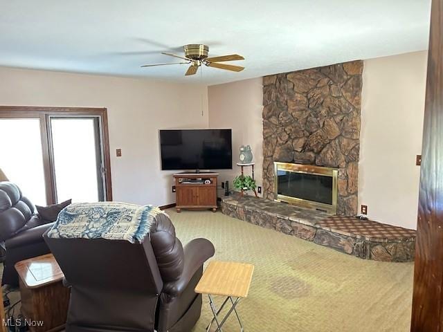 carpeted living room with ceiling fan and a fireplace