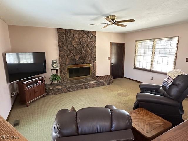 living area with ceiling fan, a fireplace, and carpet