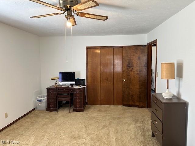 office area featuring ceiling fan, a textured ceiling, baseboards, and light carpet