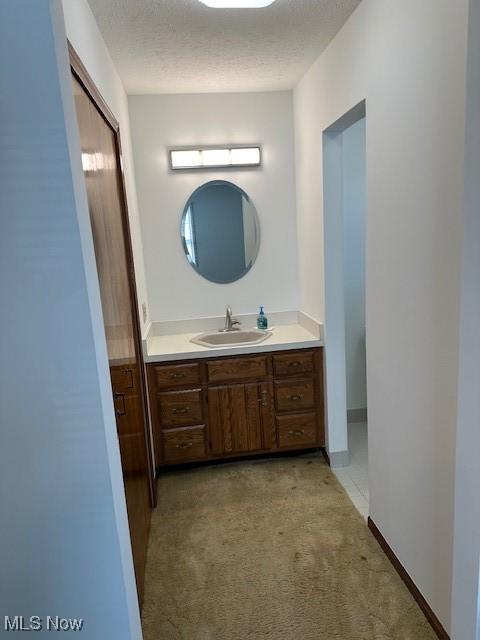 bathroom featuring baseboards, a textured ceiling, and vanity