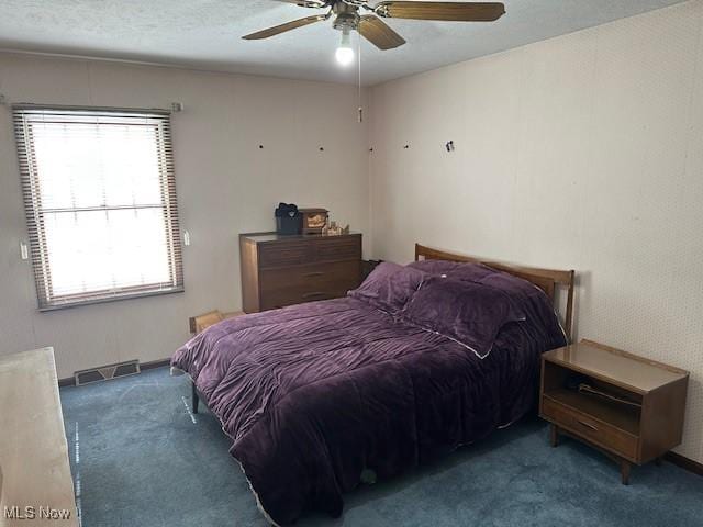 bedroom featuring visible vents, a textured ceiling, a ceiling fan, and carpet