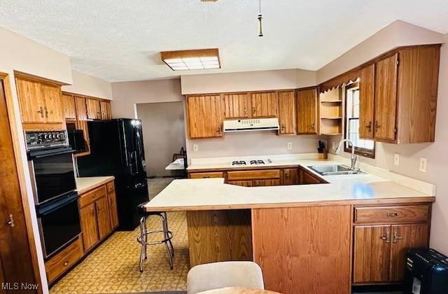 kitchen with a peninsula, a sink, black appliances, light countertops, and exhaust hood