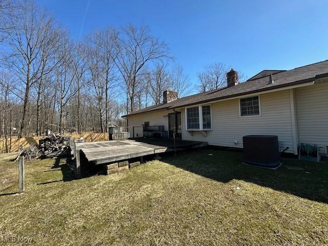 back of house with a lawn, a chimney, central AC, and a wooden deck