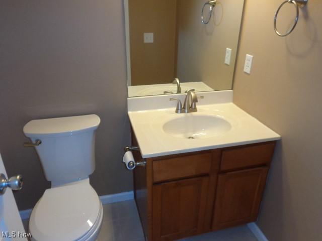 half bathroom featuring toilet, vanity, and baseboards