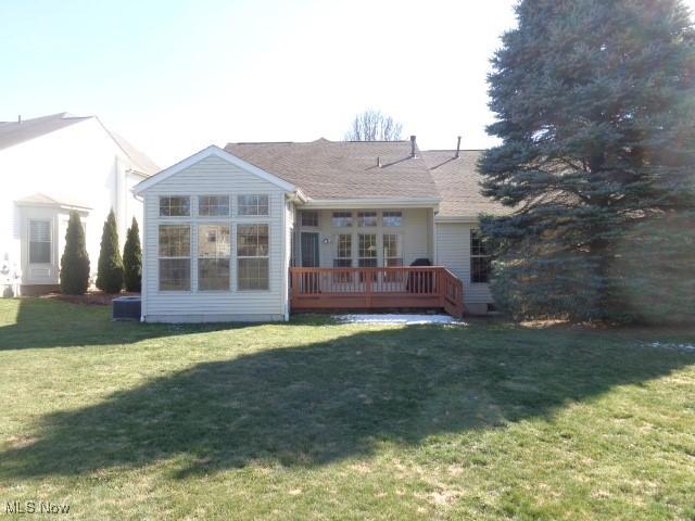 rear view of property featuring a deck and a yard