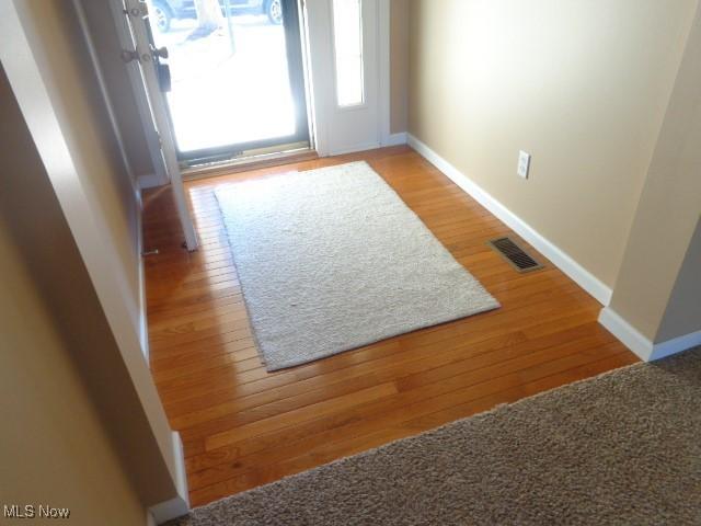 entryway featuring visible vents, baseboards, and wood finished floors