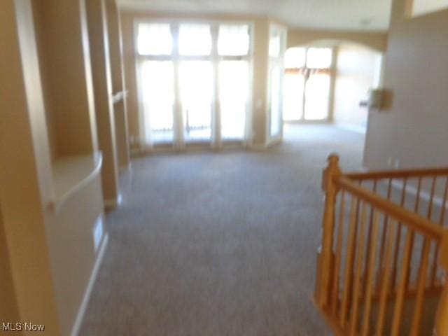 hallway with an upstairs landing, plenty of natural light, and carpet flooring