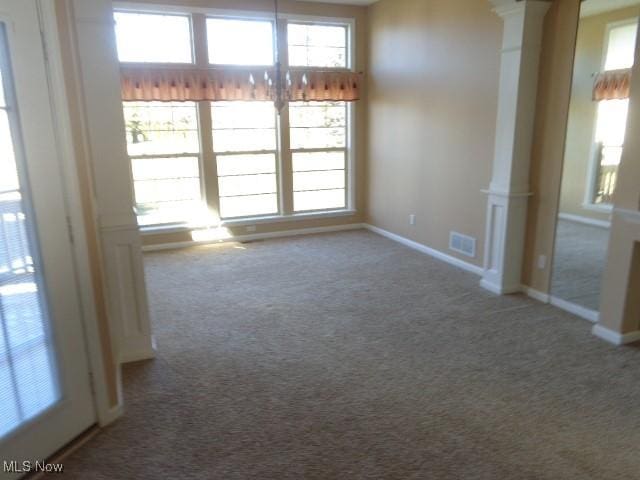 carpeted spare room with visible vents, plenty of natural light, and ornate columns