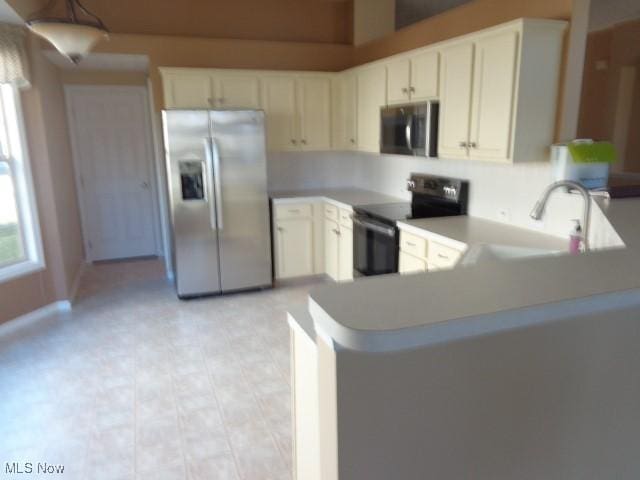 kitchen featuring a peninsula, a sink, light countertops, white cabinets, and appliances with stainless steel finishes