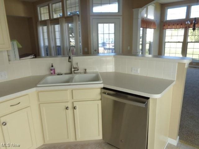 kitchen with a sink, a peninsula, light countertops, and stainless steel dishwasher