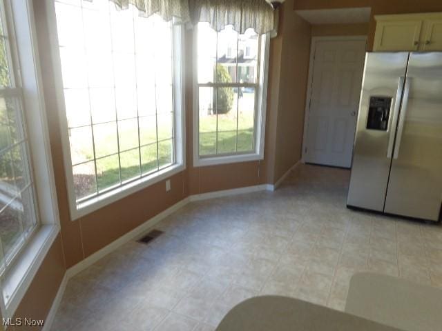 unfurnished dining area featuring visible vents, baseboards, and a wealth of natural light