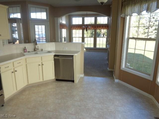 kitchen featuring a sink, a peninsula, light countertops, baseboards, and dishwasher