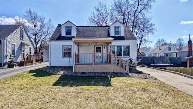 view of front of house featuring a front yard, fence, covered porch, and a shingled roof