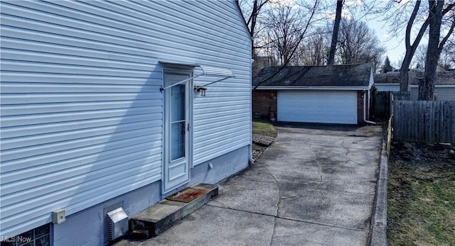 view of side of home featuring an outbuilding, a garage, and fence