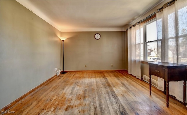 empty room with visible vents, baseboards, and wood-type flooring