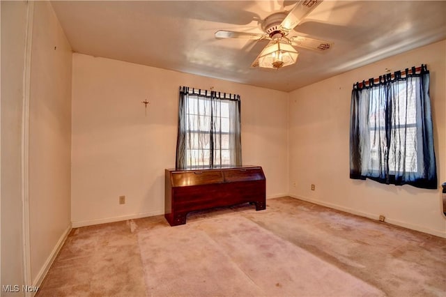 carpeted spare room with baseboards, a healthy amount of sunlight, and a ceiling fan