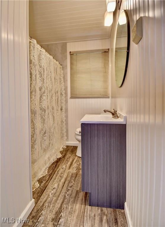 bathroom with vanity, a shower with curtain, toilet, and wood finished floors